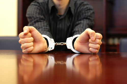 person sitting at table in handcuffs